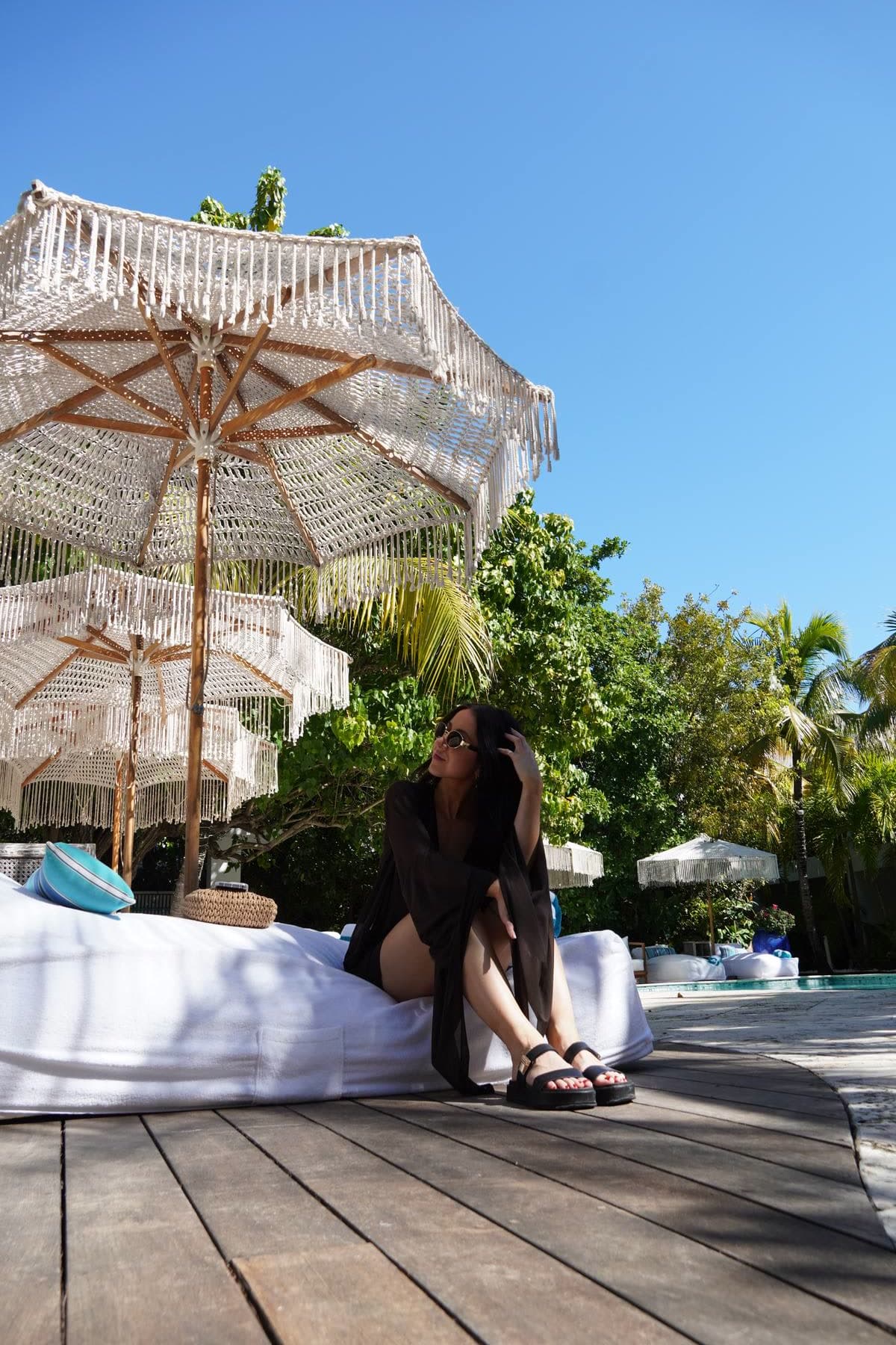 Woman on a daybed under fringe umbrellas at Oasis at Grace Bay