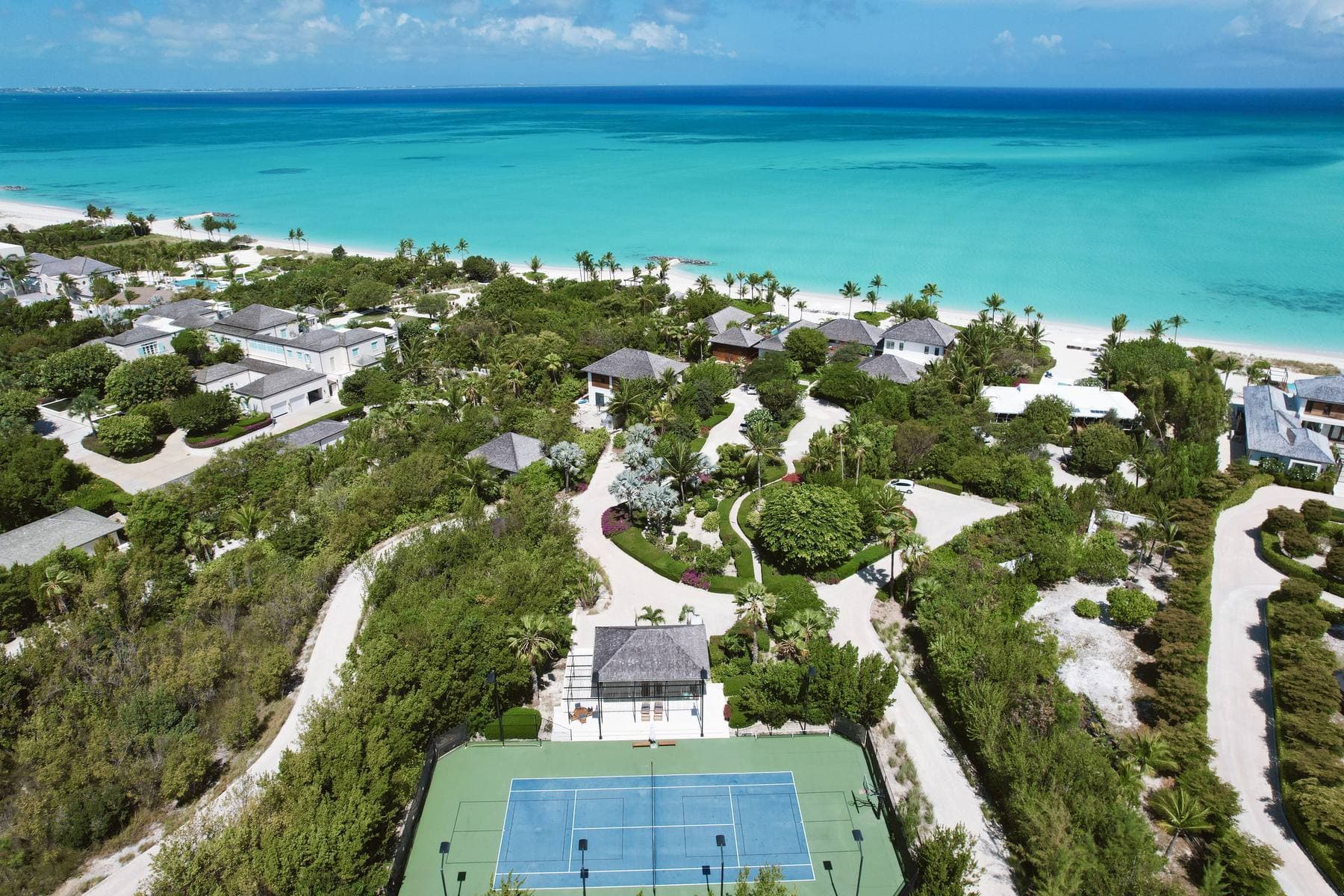 Aerial of The Source — tennis court, villas, and the shoreline